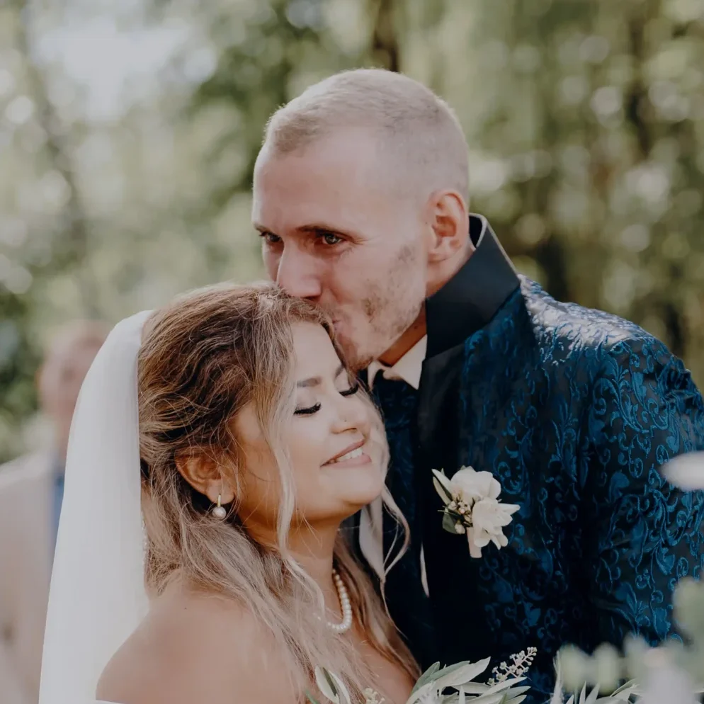 Hochzeitsfoto von Thayna und Carson, die sich an ihrem Hochzeitstag eng aneinanderlehnen.