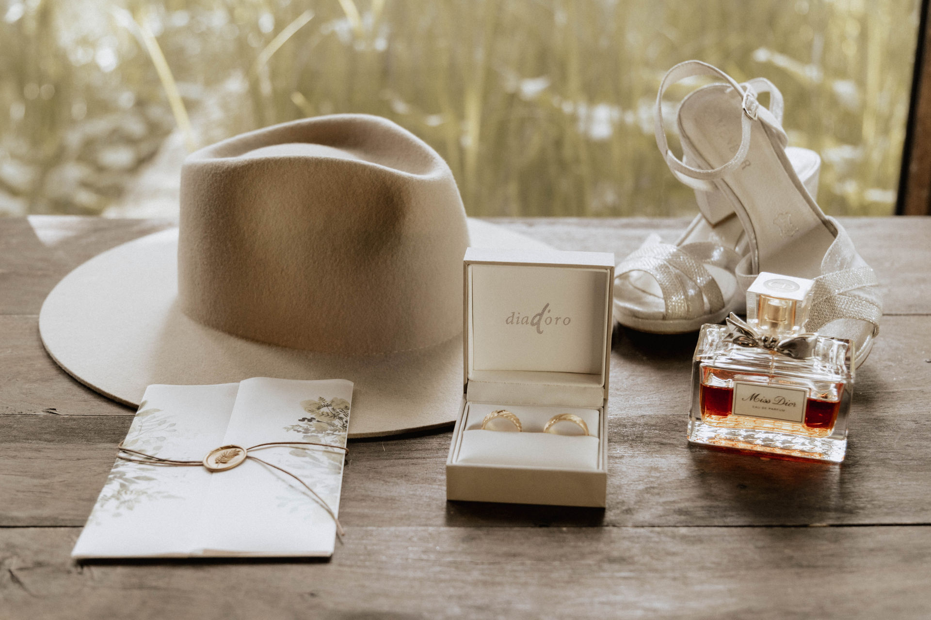 Beigefarbener Boho-Hut neben einer geöffneten Schmuckbox mit Ringen und hellen Accessoires auf einem Holztisch.