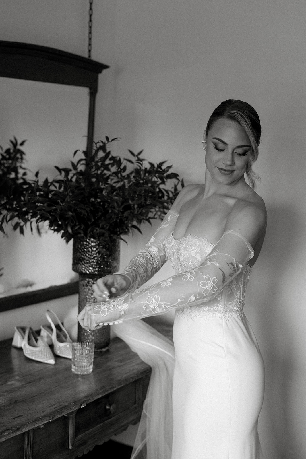 Schwarz-Weiss-Aufnahme von Sina im Brautkleid, während sie ihren Blumenstrauss betrachtet.
