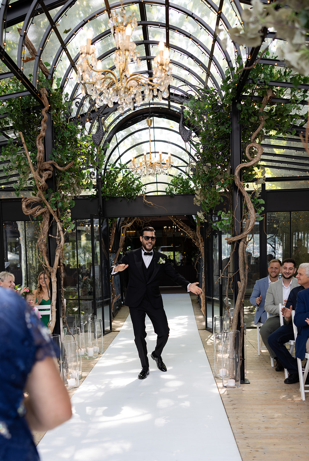 Damiano zieht in seinem dunklen Hochzeitsanzug durch einen mit Blumen geschmückten Gang zur Trauung ein.