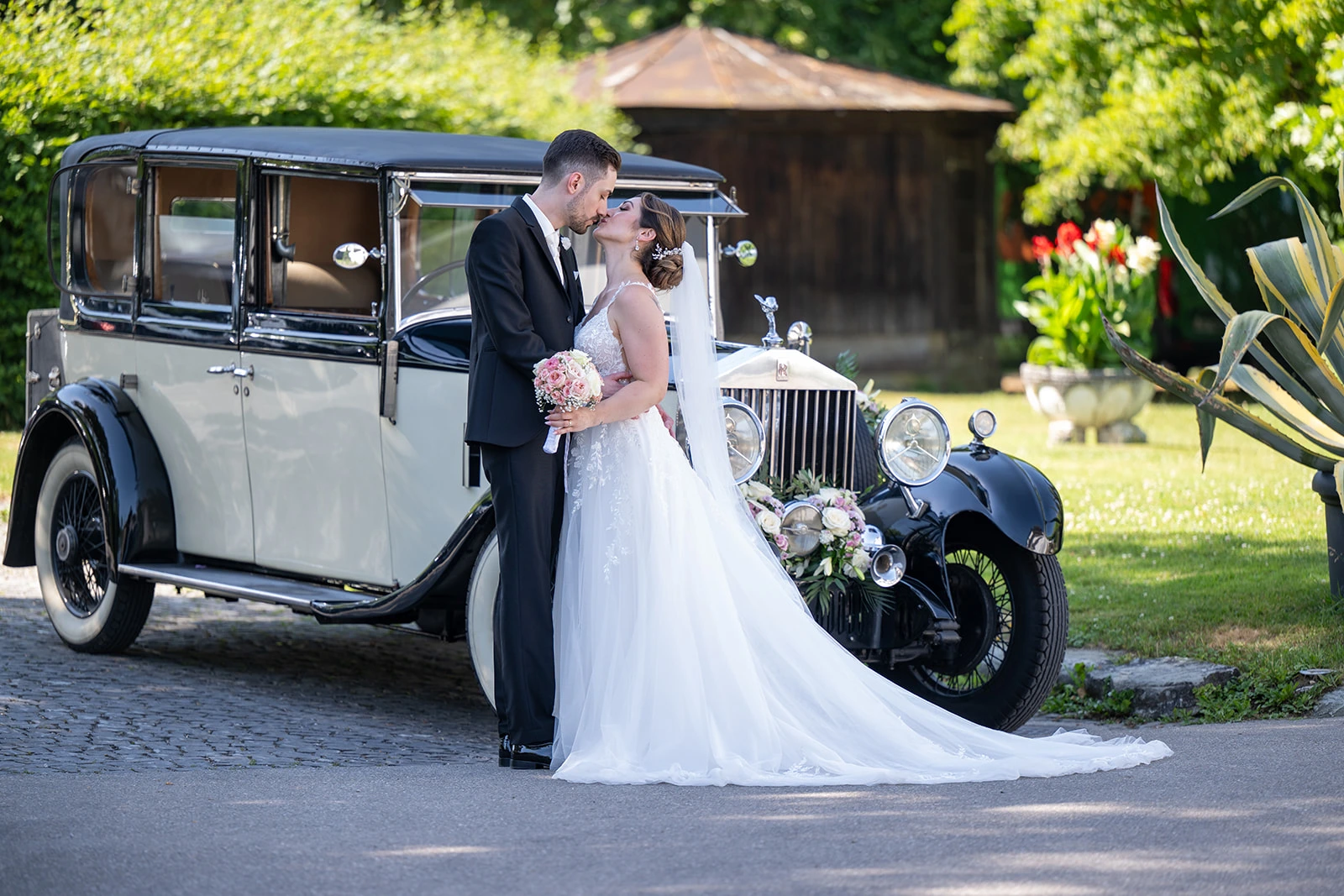 Valentina und Giacomo küssen sich neben einem historischen Bentley Oldtimer in der Schweiz.