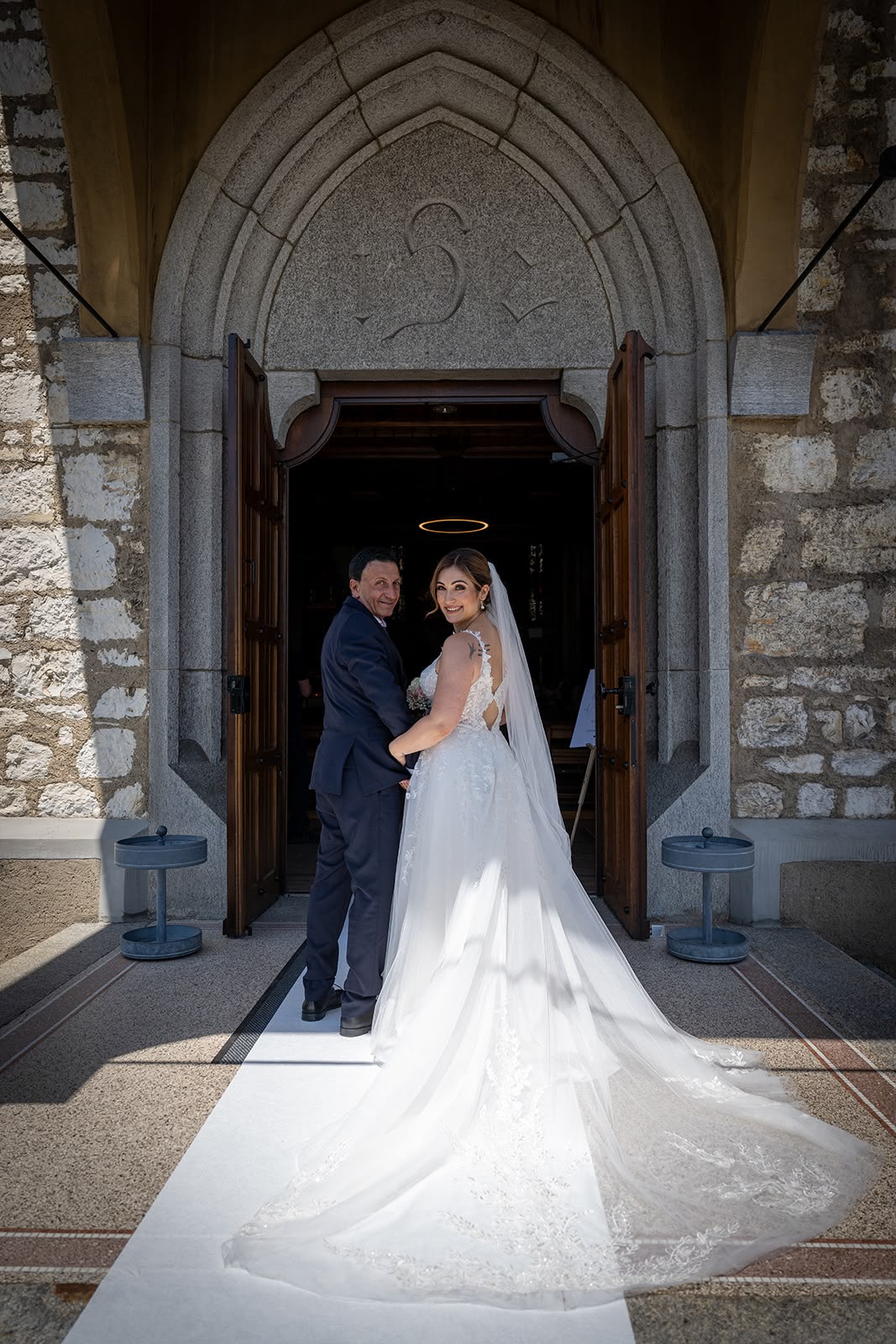 Valentina steht in ihrem weissen Brautkleid mit einer Begleitperson vor dem Eingang der Kirche, kurz vor ihrem Einzug.