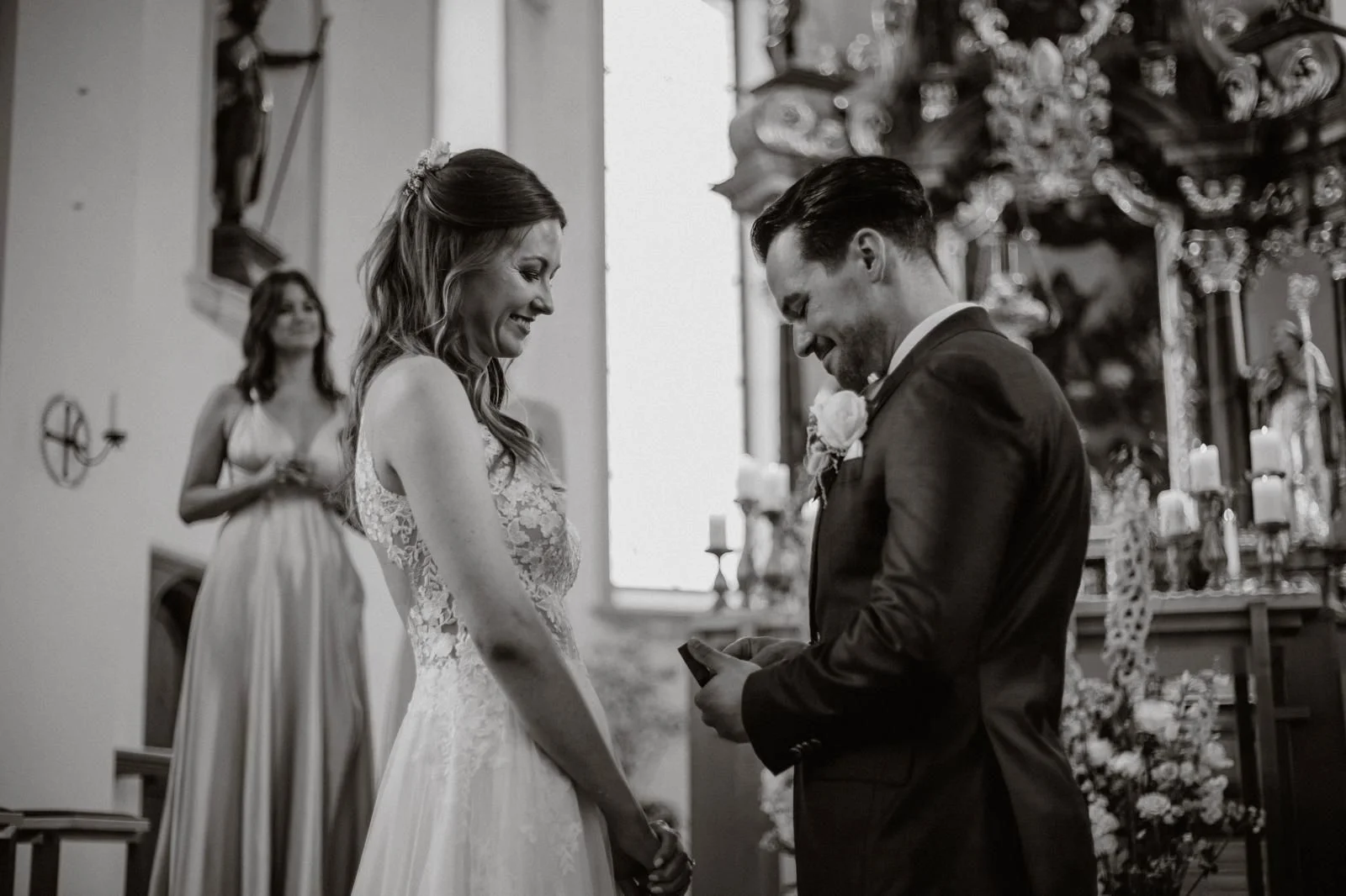 Schwarz-Weiss-Aufnahme von Céline und Philippe beim Ringtausch während ihrer kirchlichen Hochzeit.